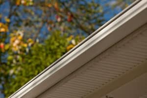 New gutters installed on a home with trees in the background.