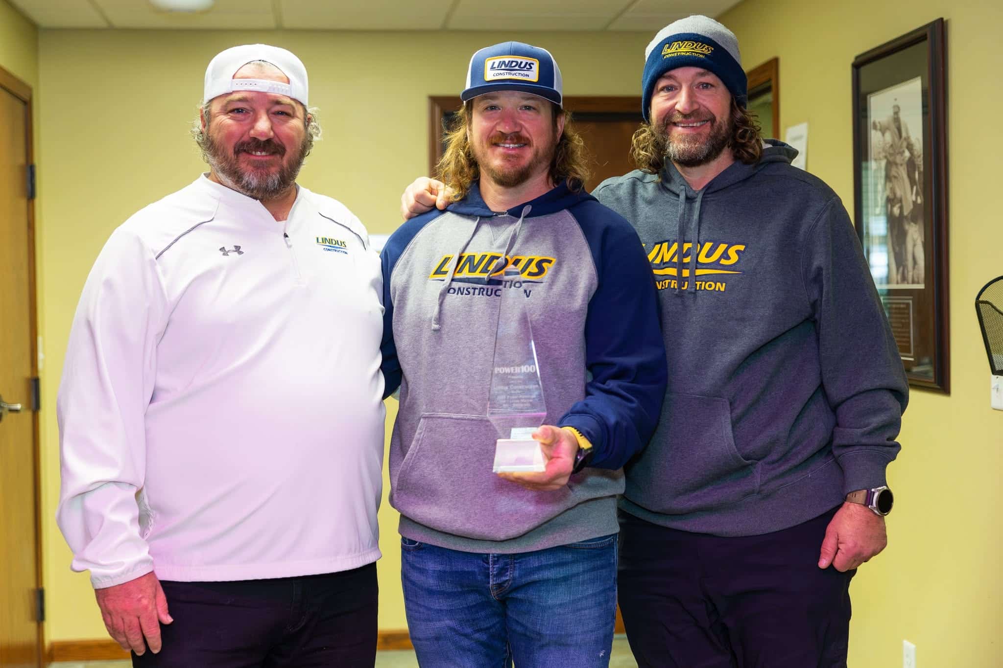 Andy, Alex, and Adam Lindus of Lindus Construction standing together with an award